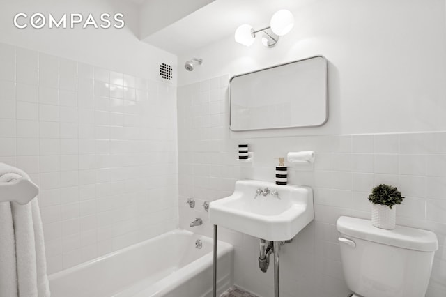 bathroom featuring toilet, tile walls, and bathtub / shower combination