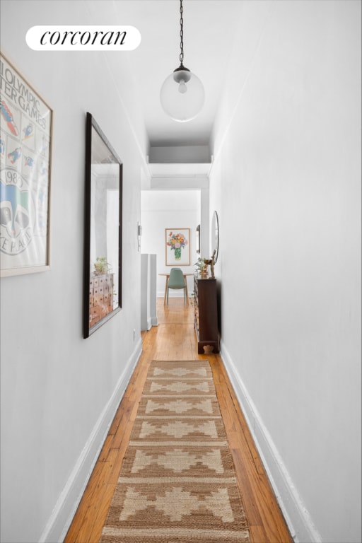 corridor featuring light wood-type flooring and baseboards