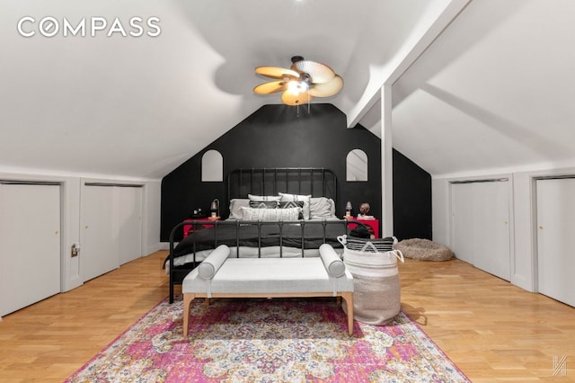 bedroom featuring vaulted ceiling, two closets, and wood finished floors