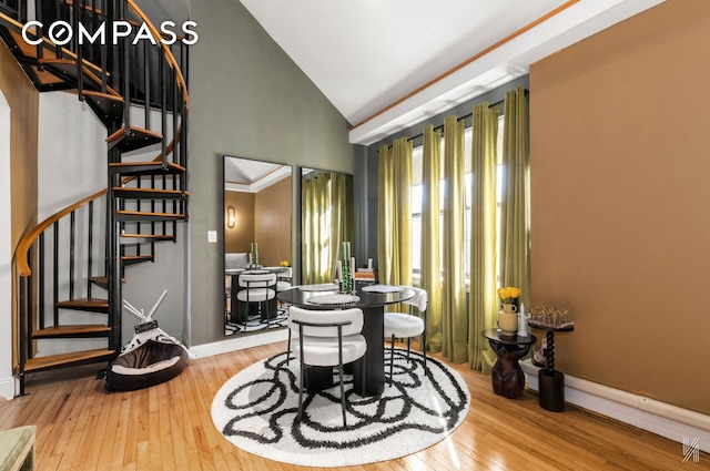 dining area featuring high vaulted ceiling, stairway, wood finished floors, and baseboards