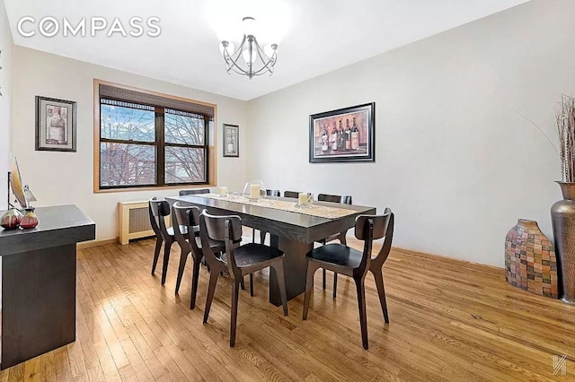 dining space featuring light wood-style floors, radiator, and an inviting chandelier