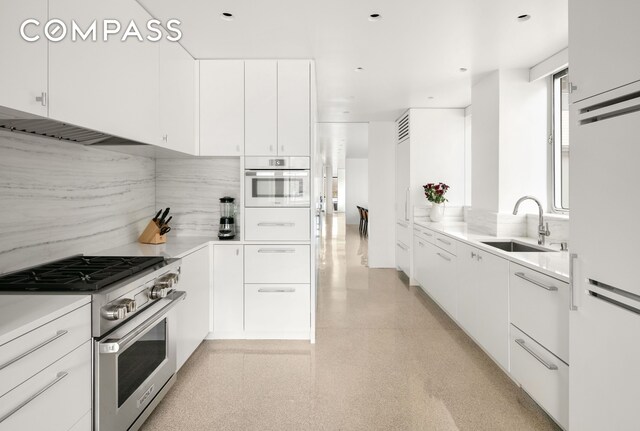 kitchen featuring white cabinetry, white appliances, tasteful backsplash, and a sink