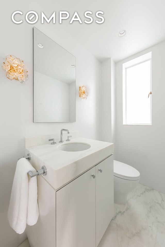 half bathroom with vanity, toilet, recessed lighting, and marble finish floor