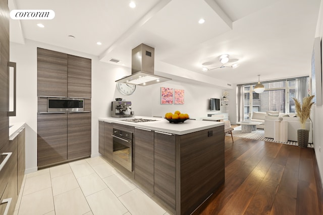 kitchen featuring a peninsula, stainless steel microwave, wall oven, island exhaust hood, and modern cabinets