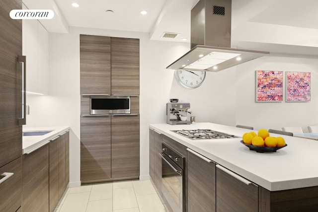 kitchen with light countertops, stainless steel appliances, island exhaust hood, visible vents, and modern cabinets