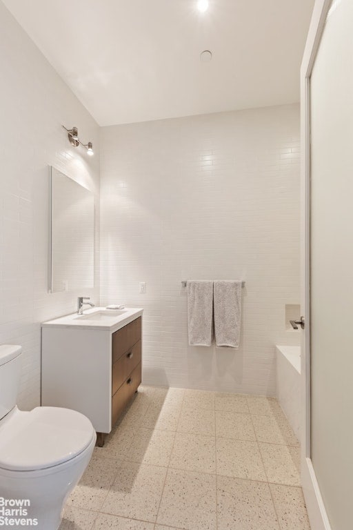 full bathroom with toilet, vanity, tile walls, and a tub