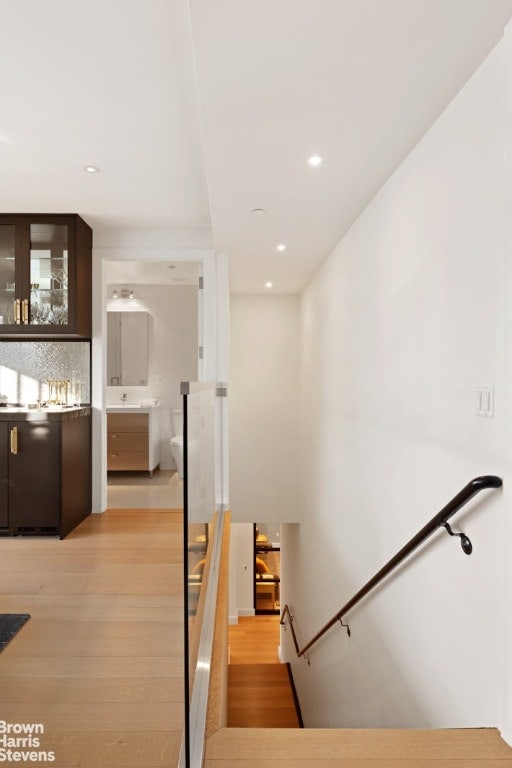 stairway with wood finished floors and recessed lighting