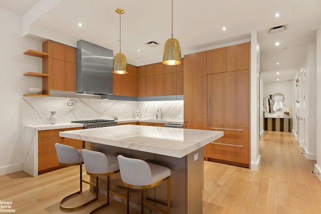 kitchen with a kitchen island, hanging light fixtures, wall chimney range hood, open shelves, and modern cabinets