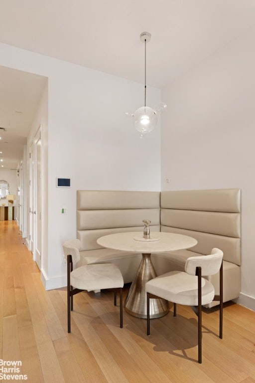 dining room featuring light wood finished floors, baseboards, and breakfast area