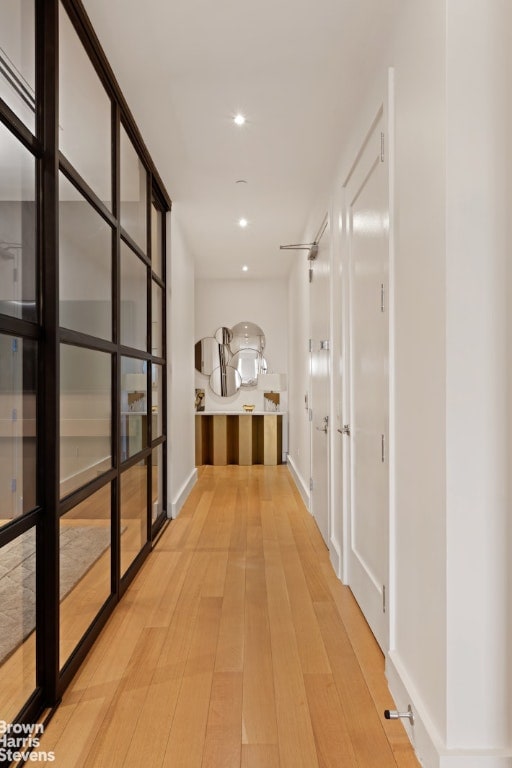 hall featuring baseboards, wood finished floors, and recessed lighting