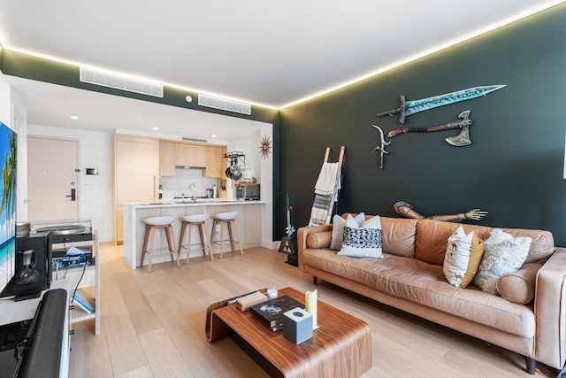 living area featuring visible vents, light wood-style flooring, and baseboards