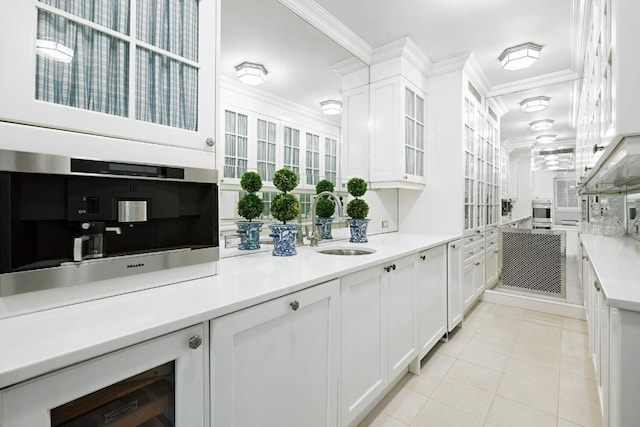 kitchen featuring a sink, white cabinetry, light countertops, and crown molding