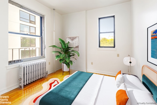 bedroom with radiator, baseboards, and wood finished floors