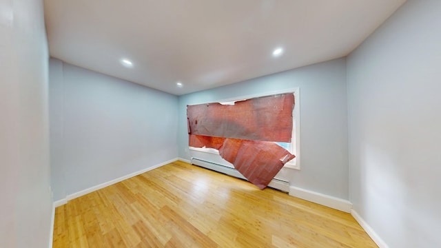 empty room with recessed lighting, a baseboard radiator, wood finished floors, and baseboards