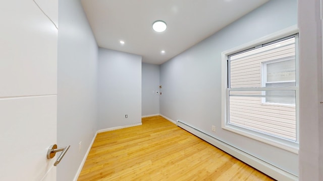 empty room featuring recessed lighting, wood finished floors, a healthy amount of sunlight, a baseboard heating unit, and baseboards