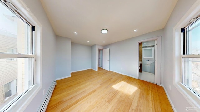 empty room featuring recessed lighting, light wood finished floors, a baseboard heating unit, and baseboards