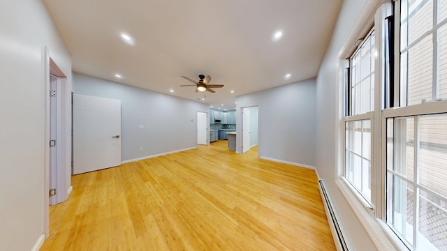 unfurnished living room with a wealth of natural light, ceiling fan, and baseboards