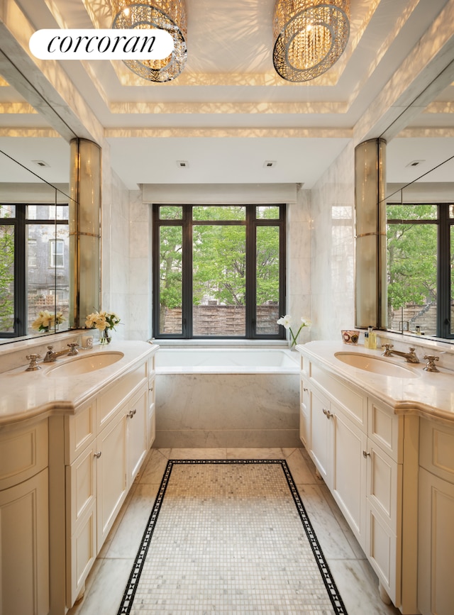 180 E 93rd St Unit 2, New York City, NY 10128 - bathroom featuring inlaid floor details, a garden tub, two vanities, a tray ceiling, and a chandelier