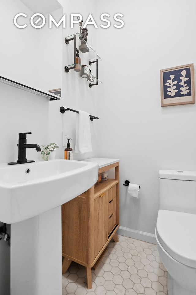 bathroom with toilet, baseboards, and a sink