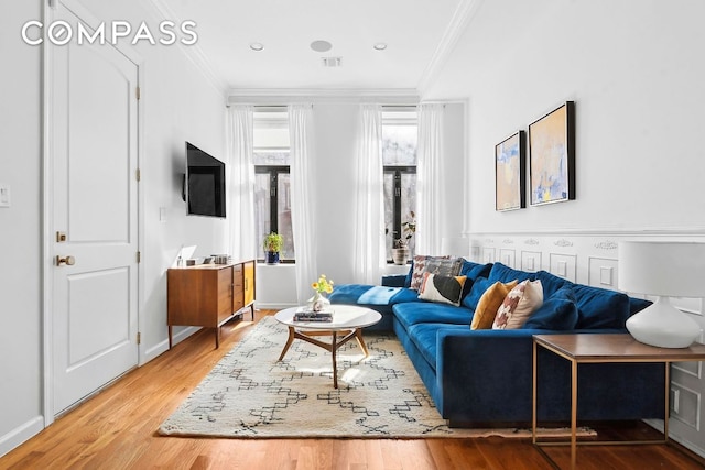 living room with baseboards, crown molding, and wood finished floors