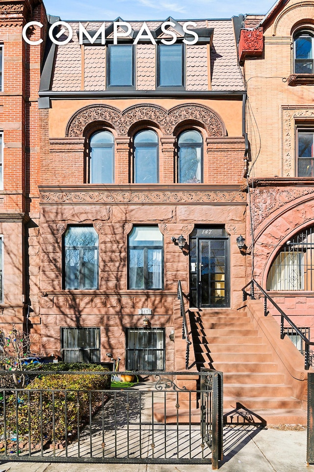 view of front of house with mansard roof and a fenced front yard