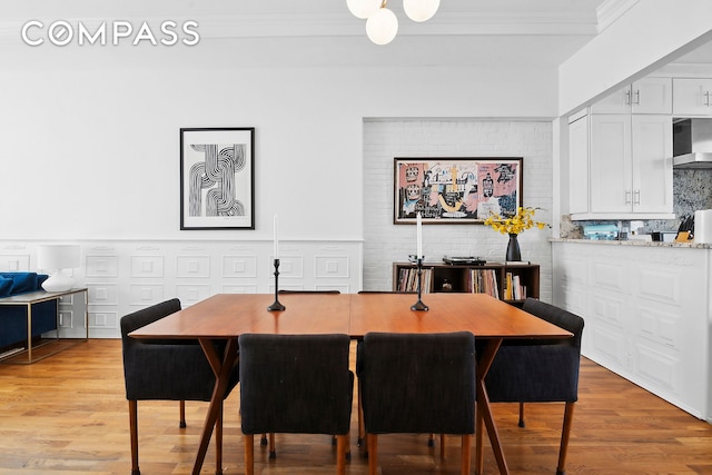 dining space with ornamental molding and light wood-type flooring