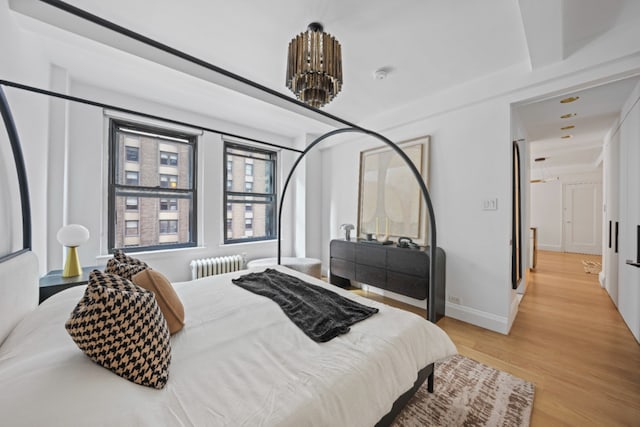 bedroom featuring light wood-style floors, radiator heating unit, and baseboards