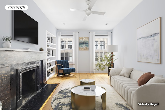 living room with wood-type flooring, a high end fireplace, and a ceiling fan