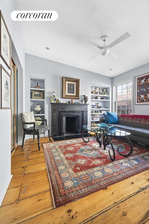 living area featuring a ceiling fan, built in features, hardwood / wood-style floors, and a fireplace