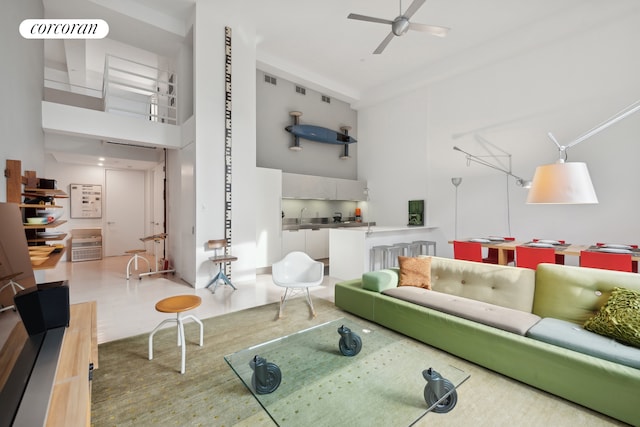 living area with visible vents, a high ceiling, and a ceiling fan