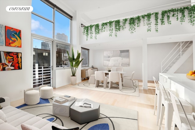 living area featuring baseboards, a high ceiling, wood finished floors, and stairs