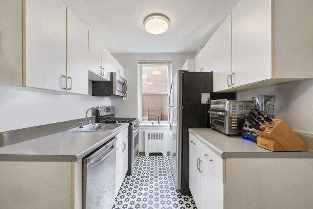 143 Bennett Ave Unit 2R, New York City, NY 10040 - kitchen featuring appliances with stainless steel finishes, a sink, white cabinetry, and light floors