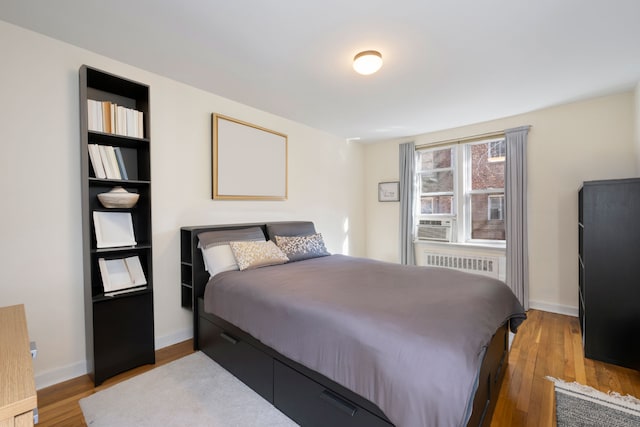bedroom with radiator, wood finished floors, and baseboards