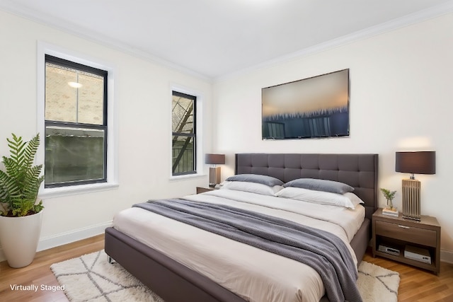 bedroom with ornamental molding, baseboards, and wood finished floors