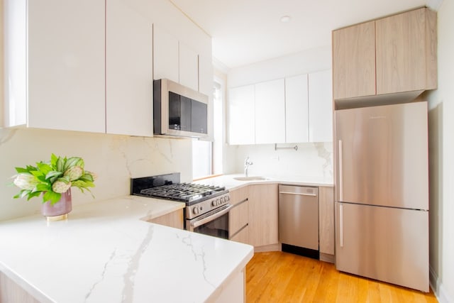 kitchen featuring white cabinets, modern cabinets, light stone counters, and stainless steel appliances