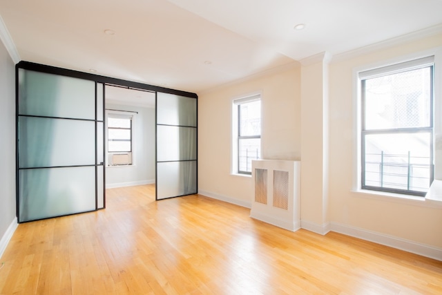 spare room featuring light wood-style floors, baseboards, and crown molding