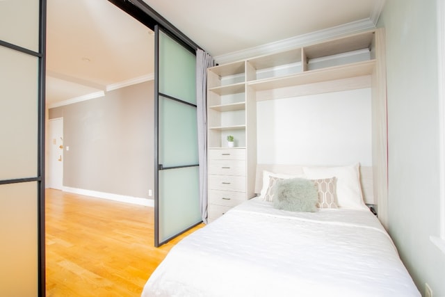 bedroom with baseboards, crown molding, and wood finished floors