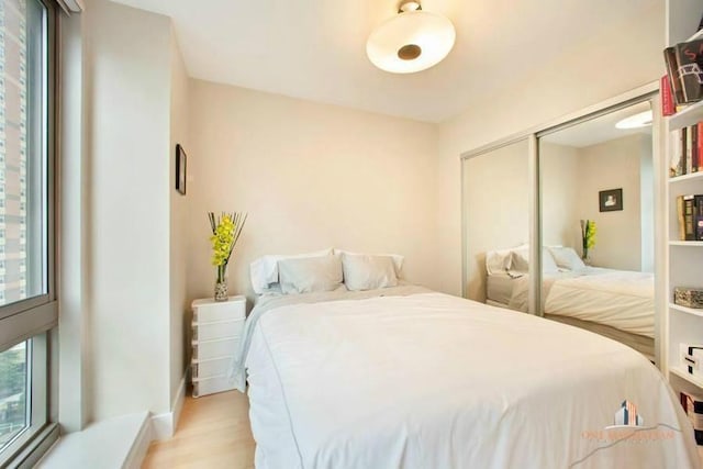 bedroom with light wood finished floors, a closet, and baseboards