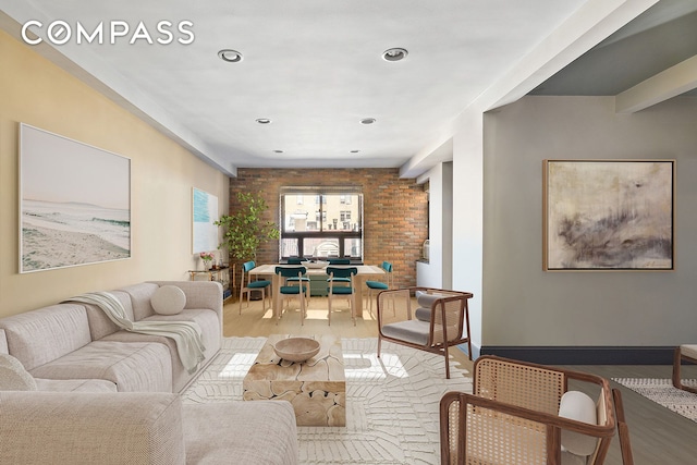 living room with baseboards, wood finished floors, and brick wall