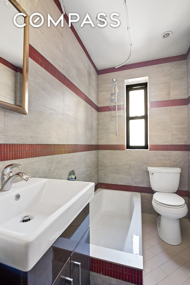 bathroom featuring a bath, a sink, tile walls, toilet, and tile patterned floors