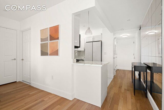 hall with light wood finished floors and baseboards