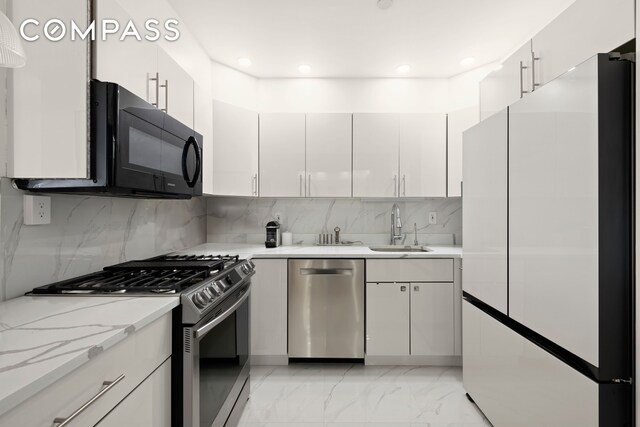 kitchen with white cabinets, appliances with stainless steel finishes, decorative backsplash, and a sink