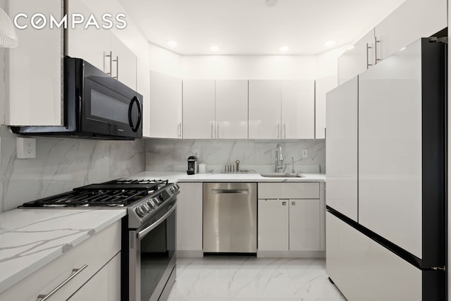 kitchen with stainless steel appliances, a sink, backsplash, white cabinets, and recessed lighting