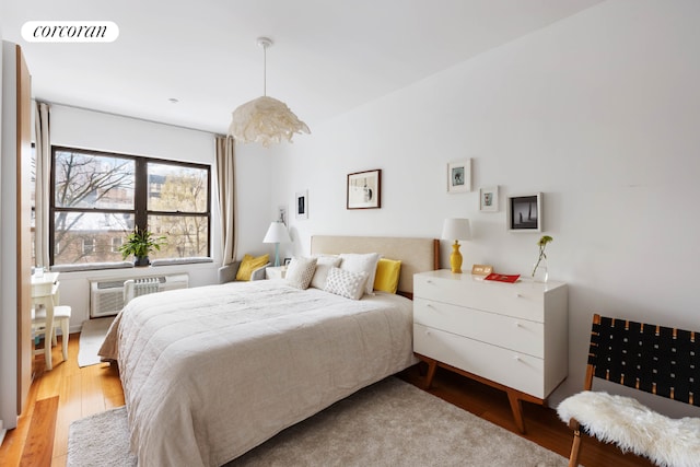 bedroom with an AC wall unit, visible vents, and light wood-style floors