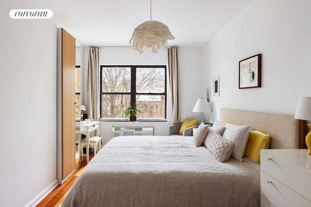 bedroom featuring baseboards, visible vents, wood finished floors, and an AC wall unit