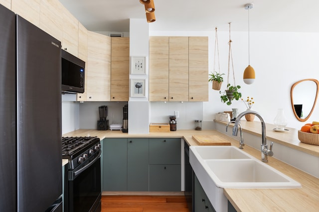 kitchen with range with gas stovetop, freestanding refrigerator, hanging light fixtures, light countertops, and a sink