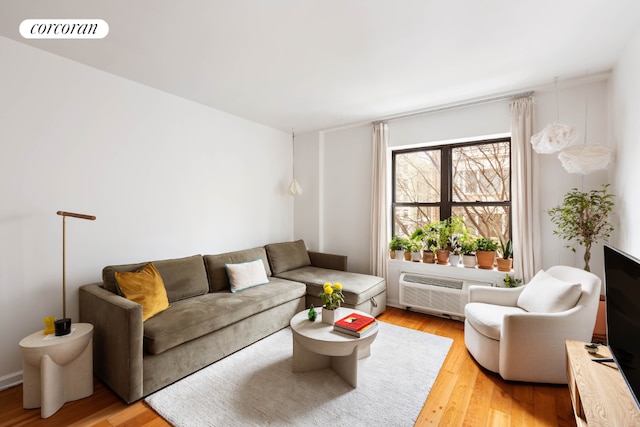 living area with light wood finished floors, a wall unit AC, and visible vents