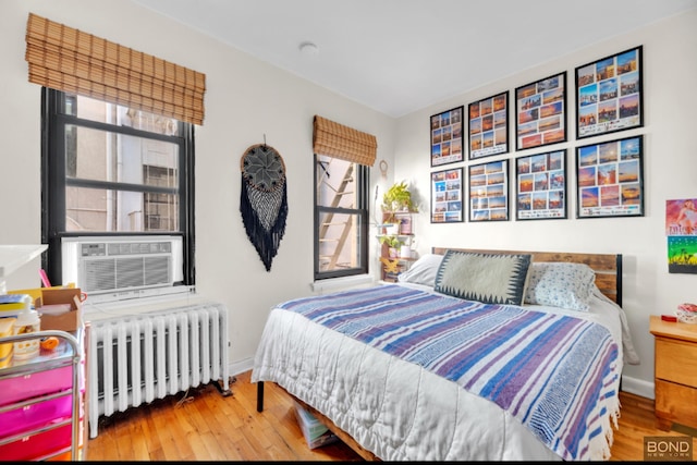 bedroom featuring radiator, baseboards, cooling unit, and wood finished floors