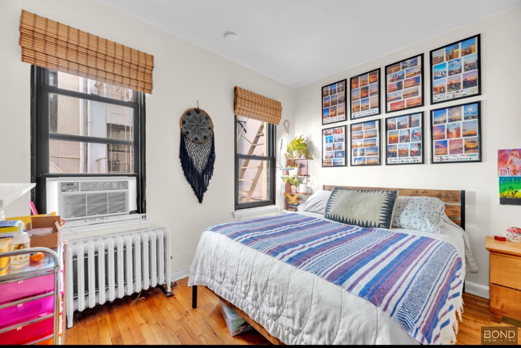 238 E 30th St Unit 2W, New York City, NY 10016 - bedroom with radiator heating unit, baseboards, cooling unit, and wood finished floors