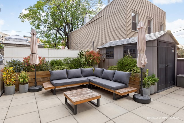 view of patio / terrace with an outbuilding, fence, a storage unit, and an outdoor hangout area